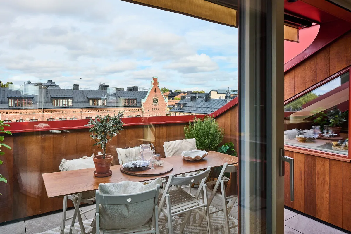 Terrass sedd genom öppen glasdörr, med trädäck och röd plåtdetalj