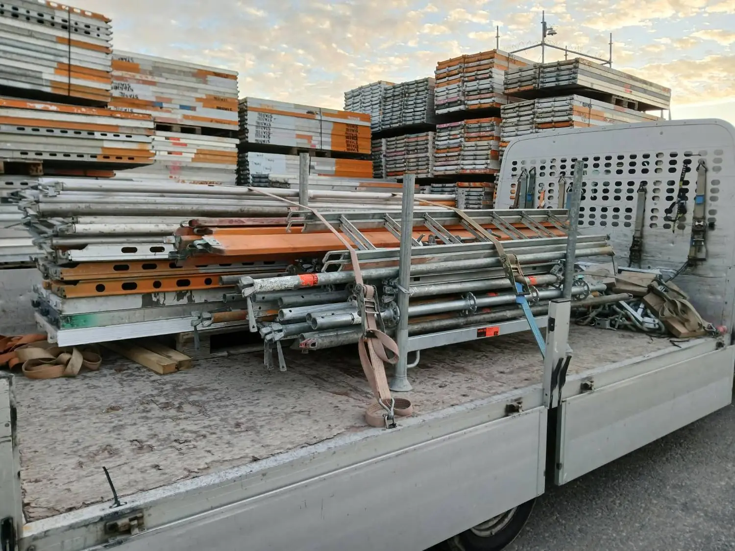 Ställningsmaterial på flak framför upplaget med plank märkta STABIL