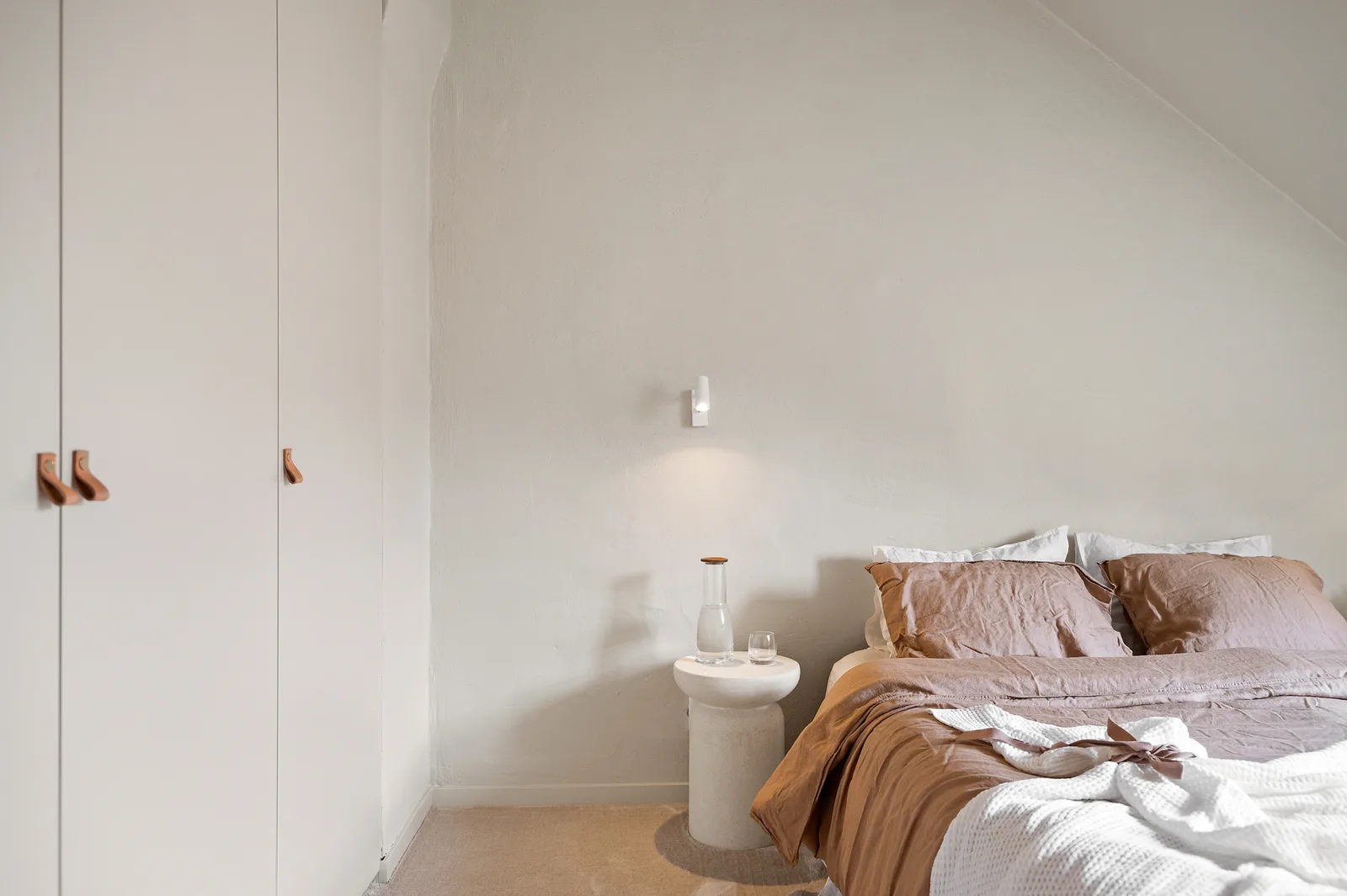 Sovrum med vit garderob och säng med bruna lakan
